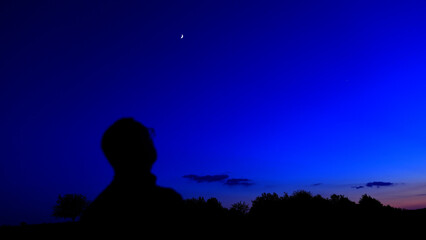 Silhouette of a person in nature observing night sky, Moon, stars and planets from a remote location. © astrosystem