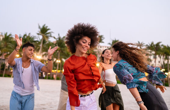 Relaxed golden hour lifestyle of young friends on a tropical beach, enjoying the warm sunset