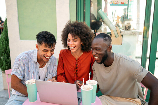 Students gather for a friendly cafe study session, learning together with a laptop, discussing ideas