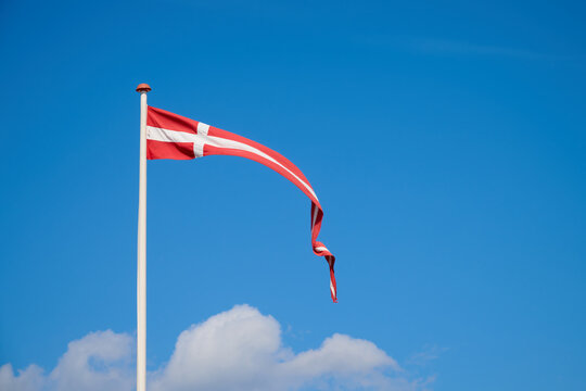 Danish flag on a mast waving in the wind.