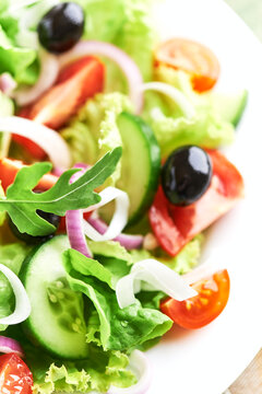 Salad with Olives, Tomatoes and Cucumber on wooden Background. Healthy Snack Idea. Close up