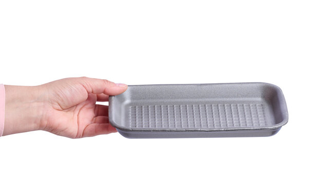 A woman's hand holding an empty grey foam food tray on isolated background.