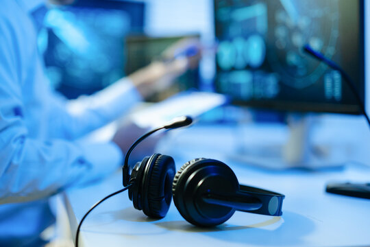 Headset on desk with professional flight controller examining radar displays and data screens in a modern command center.