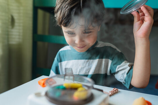 Smiling boy cooks play dough in a toy kitchen at home