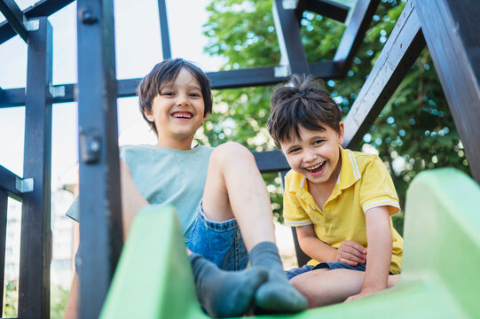 Two happy boys enjoy a playground slide outdoors