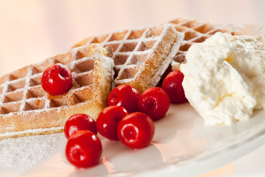Wafers with icing sugar, whipped cream and cherries, close up