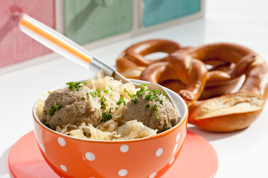 Bowl of liver dumplings with sauerkraut and pretzel, close up