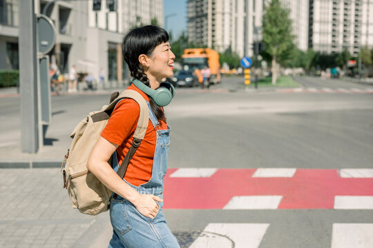 Woman walking across city street in casual outfit with backpack