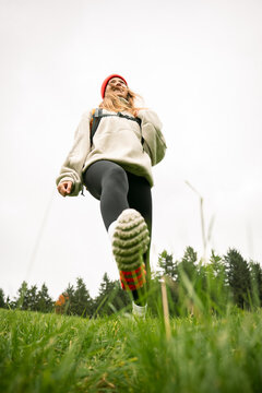 Happy woman with backpack hiking in nature stepping over camera