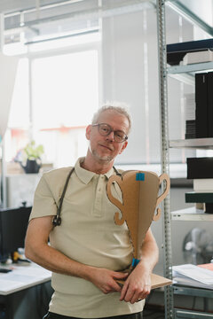 Male doctor holds a cardboard trophy in the office
