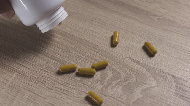 Pills spilled out from white bottle on wooden table top view