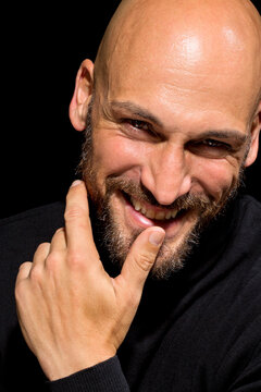 Portrait of smiling man with finger on mouth in front of black background