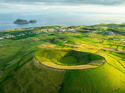 Pico Dona Joana Volcanic Cone, Patchwork Fields, Pasturelands and Cabras Islets at Sunset. Atlantic Ocean. Terceira Island, Azores, Portugal. Aerial View