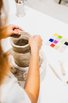 Female potter shapes a clay vase in an indoor workshop