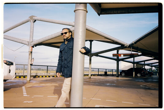 A contemplative man leans against a pillar in a parking garage