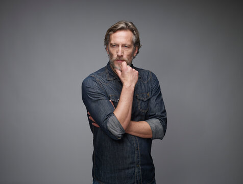 Portrait of pensive mature man in front of grey background