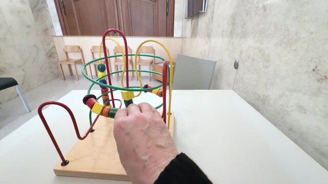 A close-up view of a colorful wooden bead maze toy designed to develop fine motor skills and hand-eye coordination in young children. Close-up POV shot