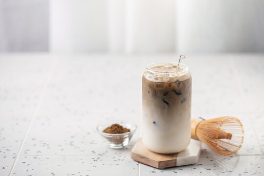 Refreshing cold iced hojicha tea latte in a tall glass, perfect for a summer day. Copy space