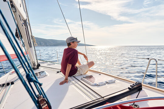 Teenage boy relaxes on a sailboat deck in the Adriatic Sea