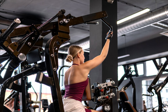 Woman performs upper body workout on a gym machine