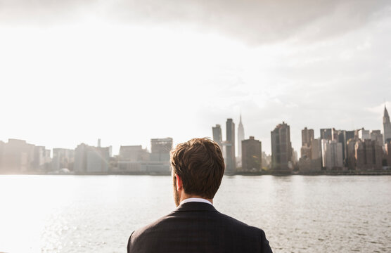 USA, New York City, back view of businessman looking at skyline of Manhattan