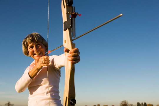 Senior adult woman using bow and arrow