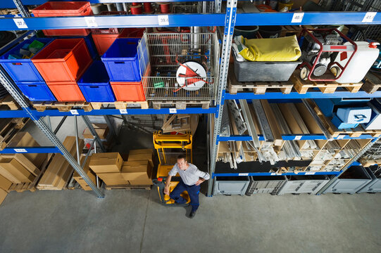 A man stands by a pallet transporter in a Munich warehouse, highlighting the busy industrial atmosphere of Bavaria, Germany