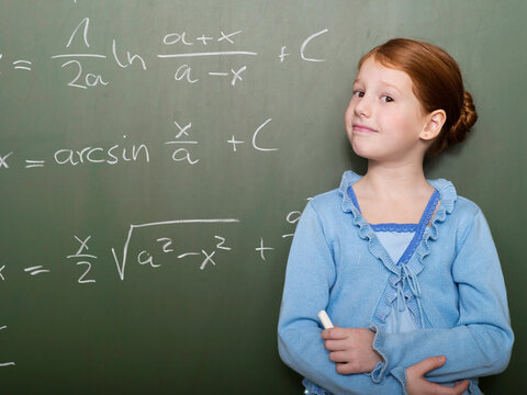 Girl (4-7) standing by blackboard, portrait, close-up