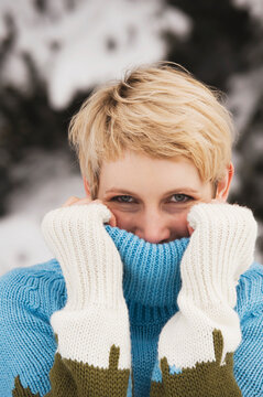 Italy, South Tyrol, Young woman, covering face with turtleneck pullover, portrait, close-up