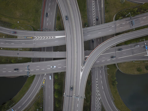 Aerial view of a complex highway interchange with multiple lanes and moving cars, surrounded by green spaces and water in Gothenburg, Vastra Gotaland County, Sweden.