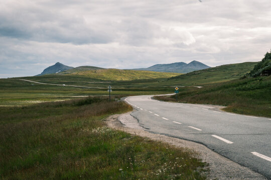 Winding coastal road E69 leading through green subarctic tundra hills towards North Cape on Mager&oslash;ya island, Troms og Finnmark, Norway