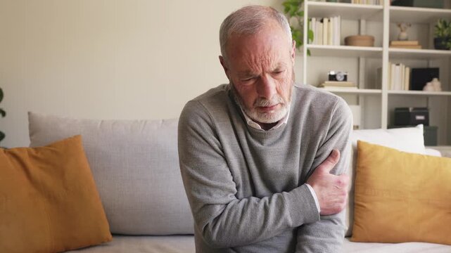 Elderly man suffering from sudden arm pain at home