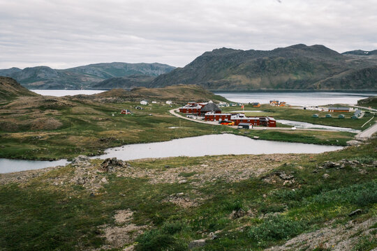 Overview of red wooden houses clustered near an arctic freshwater lake amidst tundra hills on Mager&oslash;ya island, Nordkapp, Finnmark, Norway