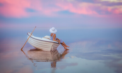 White wooden rowboat floating on calm pastel sea at sunrise © Vaiva