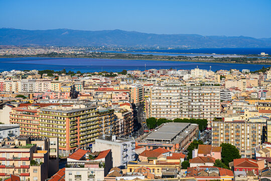 Aerial view over the rooftops of Cagliari towards the Molentargius-Saline Regional Natural Park lagoon and mountains, Sardinia, Italy
