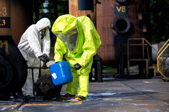 Hazmat workers in protective suits handle a chemical container during hazardous material response training