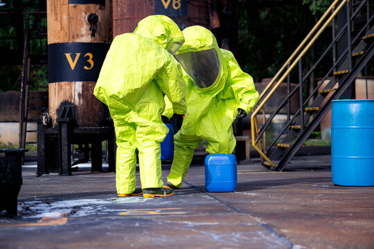 Hazmat workers in protective suits handle a chemical container during hazardous material response training