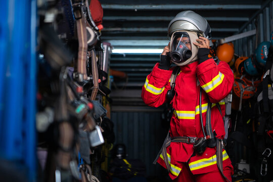 Firefighter wearing protective clothing and breathing equipment prepares a helmet