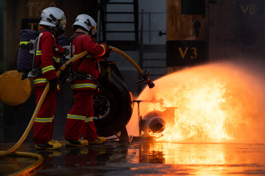 Firefighters in protective gear spray water to extinguish flames