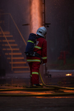 Firefighter wearing protective equipment operates a water hose