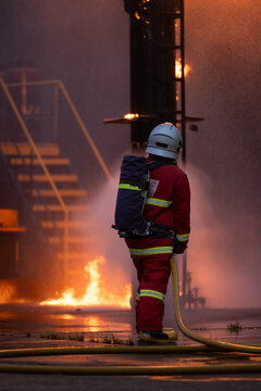 Firefighter wearing protective equipment operates a water hose