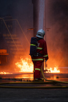 Firefighter wearing protective equipment operates a water hose