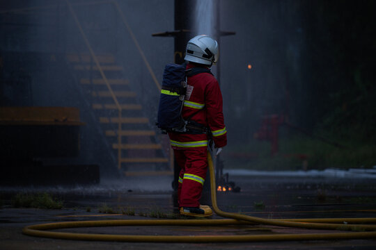 Firefighter wearing protective equipment operates a water hose