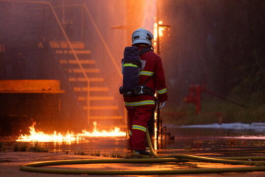 Firefighter wearing protective equipment operates a water hose