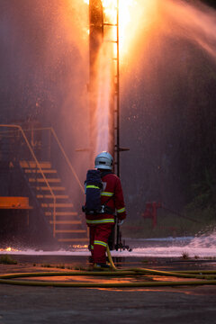 Firefighter wearing protective equipment operates a water hose