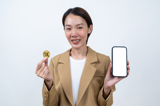 Asian businesswoman showing gold bitcoin coin and smartphone mockup on isolated white background. Concept of modern crypto platform and online trading app.