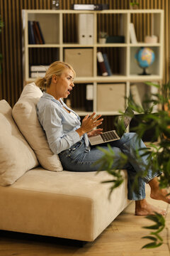 Woman Works on Laptop in Small Office Space While Sitting on Couch