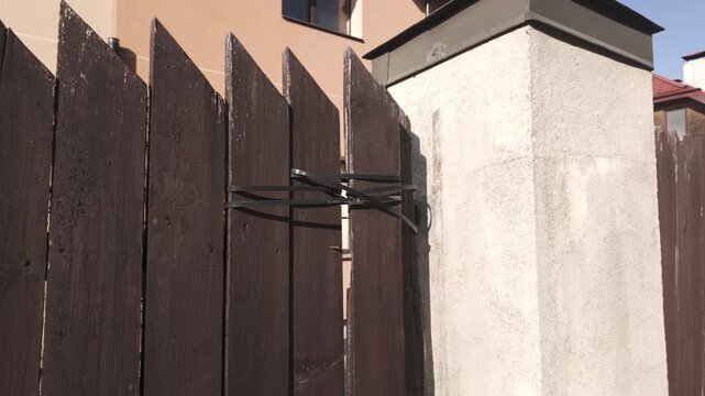 Steel support bracket reinforces weathered wooden fencing beside a suburban home