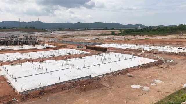 A vast land development site for a large scale terraced house project. Cleared land is prepared for new housing units. Nearby areas show ongoing residential construction in progress.