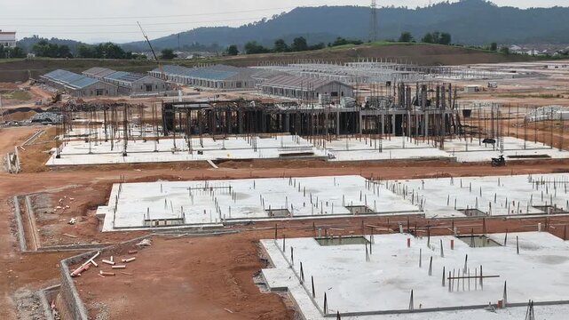 A vast land development site for a large scale terraced house project. Cleared land is prepared for new housing units. Nearby areas show ongoing residential construction in progress.